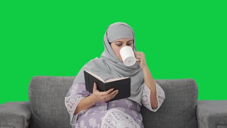 Muslim-woman-reading-a-book-and-drinking-tea-Green-screen