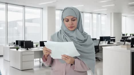 Muslim-businesswoman-reading-reports-in-office