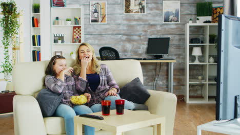 Cheerful-mother-and-daughter-sitting-on-the-couch