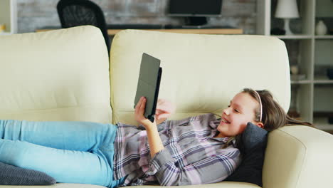 Kleines-Mädchen-Liegt-Auf-Der-Couch-Und-Benutzt-Ihr-Tablet