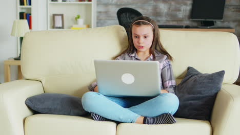 Süßes-Kleines-Mädchen-Mit-Zahnspange,-Das-Auf-Der-Couch-Sitzt-Und-Ihren-Laptop-Benutzt