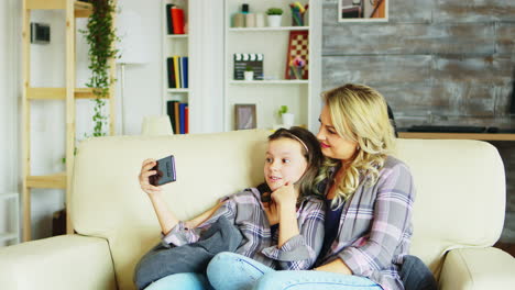Little-girl-and-her-mother-sitting-on-the-couch-in-living-room