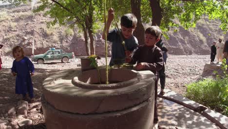 A-youngster-using-their-hands-to-gather-water-from-a-well
