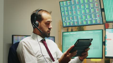 Stock-market-broker-having-a-conversation-on-headphones-while-using-tablet-computer