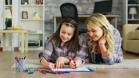 Cheerful-little-girl-lying-on-the-floor-with-her-mother-drawing