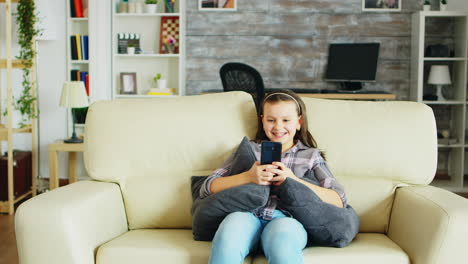 Cheerful-little-girl-with-braces-sitting-on-the-couch