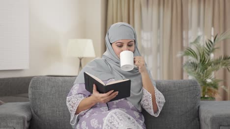Mujer-Musulmana-Feliz-Leyendo-Un-Libro-Y-Bebiendo-Té