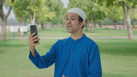 Glücklicher-Muslimischer-Mann,-Der-Im-Park-Per-Videoanruf-Spricht