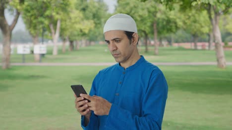 Muslim-man-chatting-on-phone-in-park