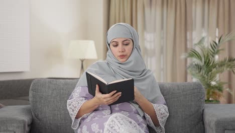 Sleepy-Muslim-woman-reading-a-book-and-drinking-tea