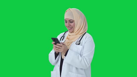 Glücklicher-Muslimischer-Arzt,-Der-Jemandem-Auf-Dem-Grünen-Bildschirm-Des-Telefons-Eine-Nachricht-Sendet