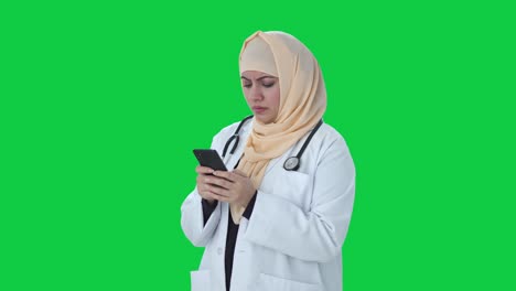 Wütender-Muslimischer-Arzt,-Der-Jemandem-Auf-Dem-Grünen-Bildschirm-Des-Telefons-Eine-Nachricht-Sendet