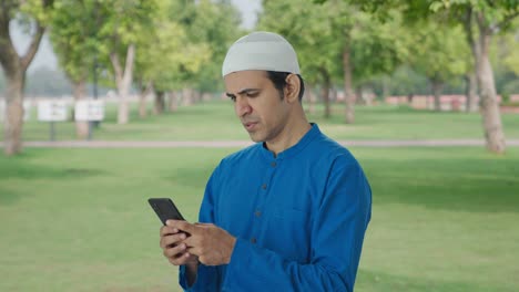 Ernsthafter-Muslimischer-Mann,-Der-Im-Park-Telefoniert