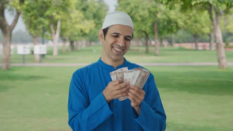 Glücklicher-Muslimischer-Mann,-Der-Im-Park-Geld-Zählt
