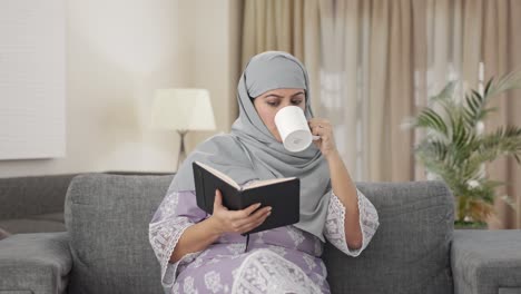Mujer-Musulmana-Leyendo-Un-Libro-Y-Bebiendo-Té