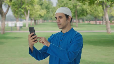 Serious-Muslim-man-using-Phone-in-park