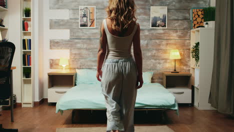 Beautiful-blonde-woman-in-pajamas-dropping-back-on-her-bed