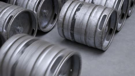 Multiple-metal-beer-kegs-rolled-on-the-ground-sequential.-A-camera-moves-back-in-an-endless,-seamless-loop.-Soft-light-illuminates-surfaces-of-cold,-steel,-worn-barrels.-Warehouse-storage-work.