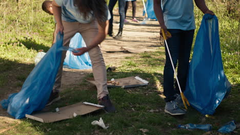 Diverse-men-volunteers-pick-up-rubbish-and-plastic-trash-with-tongs