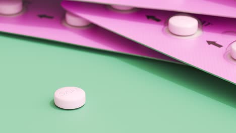 Single-pink-birth-control-pill-on-a-green-table.-Few-full-packages-of-contraceptive-pills-in-a-feminine-blister.-Clean,-colorful-animation-of-modern-anti-pregnancy-medicine.-Camera-smooth-zoom-out.