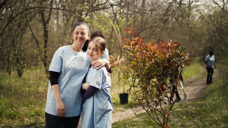Portrait-of-mother-and-daughter-volunteering-to-clean-up-a-forest-area