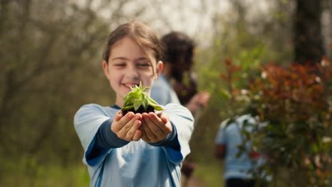 Little-kid-volunteer-holding-a-small-seedling-with-natural-soil-in-hands