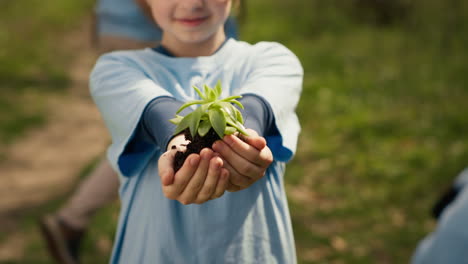 Small-child-holding-soil-with-a-green-sprout-in-her-hands