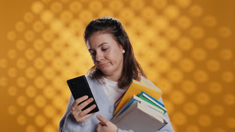 Upset-woman-holding-stack-of-book,-preparing-for-school-exam-using-phone