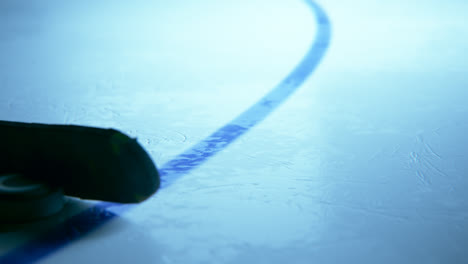 Ice-hockey-rink-with-game-net-on-a-scratched-ice-arena-surface.-Black-hard-rubber-puck-scoring-goal-straight-into-the-net.-Slow-motion-shot-from-inside-of-goal-net.-Sport,-competition,-win-background