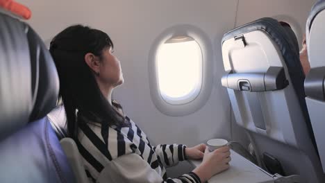 Frau-Sitzt-Im-Flugzeug,-Schaut-Aus-Dem-Fenster-Und-Trinkt-Kaffee.