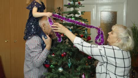 Mädchen-Mit-älterer-Oma-Und-Opa-Schmücken-Künstlichen-Weihnachtsbaum-Mit-Ornamenten-Und-Spielzeug