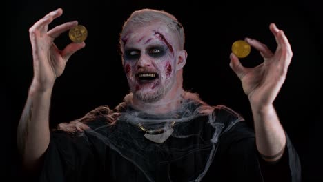Zombie-man-with-make-up-with-fake-wounds-scars-showing-golden-bitcoins,-mining-btc-cryptocurrency