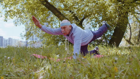 Happy-senior-grandfather-man-exercising,-making-yoga-exercise,-practicing-sports-training-at-park