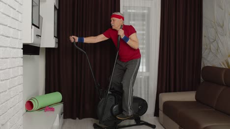 Älterer-Mann-In-Sportkleidung-Benutzt-Orbitrek-Im-Wohnzimmer-Und-Macht-Zu-Hause-Sporttraining-Und-Cardio-Übungen