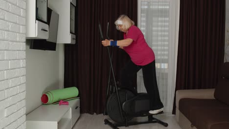 Active-healthy-senior-old-mature-woman-in-sportswear-using-orbitrek,-training-cardio-workout-at-home
