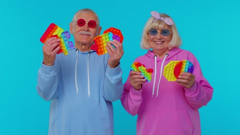 Elderly-stylish-grandmother-grandfather-showing-squeezing-anti-stress-push-pop-it-popular-toy-game