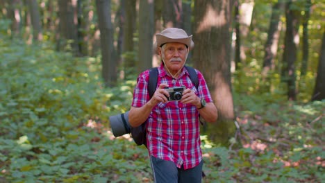 Abuelo-Anciano-En-Viaje-De-Senderismo-Explorando-La-Vida-Silvestre-Tomando-Fotos-En-El-Bosque-Con-Cámara-Retro