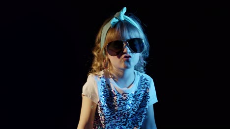Playful-blond-girl-in-blue-neon-lights-singing-on-black-background,-making-faces,-fooling-around
