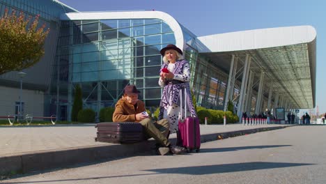 Bored-senior-husband-and-wife-retired-tourists-waiting-for-delayed-boarding-near-airport-terminal