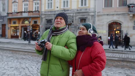 Grandfather-taking-photo-pictures-with-grandmother-on-retro-camera-in-winter-snowy-town-Lviv-Ukraine
