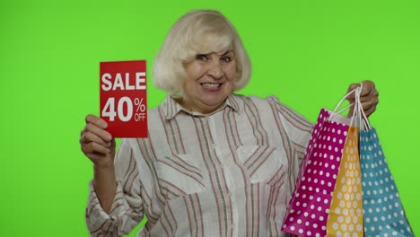 Ältere-Frau-Zeigt-Bis-Zu-40-%-Rabatt-Auf-Aufschriftschild-Und-Einkaufstüten.-Chroma-Key-Hintergrund