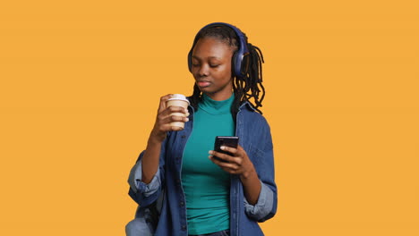 Woman-scrolling-on-smartphone,-drinking-coffee,-studio-background