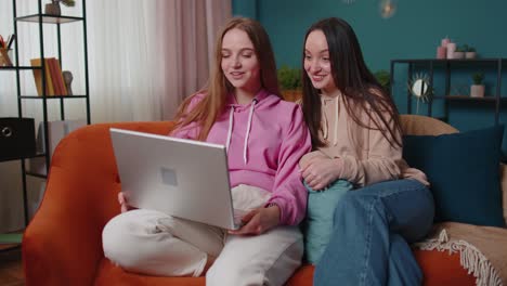 Young-teen-girls-friends-siblings-smiling-making-online-video-call-communication-on-laptop-notebook