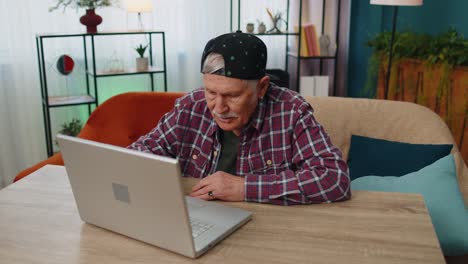 Amazed-senior-grandfather-use-laptop-computer,-receive-good-news-message,-shocked-by-sudden-win,-wow