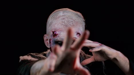 Zombie-Mann-In-Krämpfen-Mit-Make-up-Und-Falschen-Wunden,-Narben-In-Weißen-Kontaktlinsen,-Die-Versuchen,-Angst-Zu-Machen