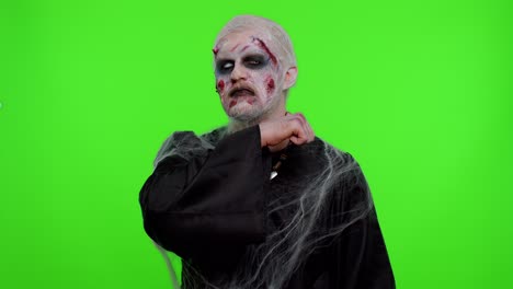 Sinister-man-Halloween-zombie-trying-to-scare-showing-killing-gesture,-runs-a-finger-along-his-neck