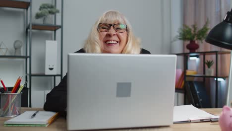 Senior-mature-older-business-woman-hiding-behind-laptop-computer,-making-funny-face,-fooling-around
