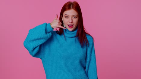 Cheerful-girl-in-blue-sweater-looking-at-camera-doing-phone-gesture-like-says-hey-you-call-me-back