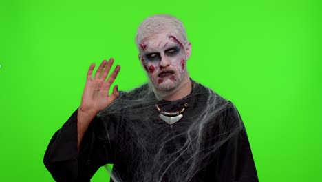 Creepy-Halloween-zombie-man-smiling-friendly-waving-hands-gesturing-hello-or-goodbye,-welcoming