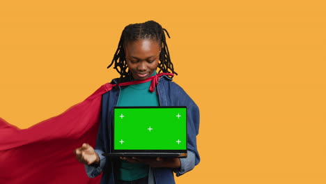 Portrait-of-jolly-teenager-acting-as-superhero-presenting-green-screen-laptop